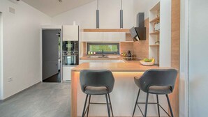 Eine moderne Küche mit Kochinsel, Barhocker und integrierten Geräten.