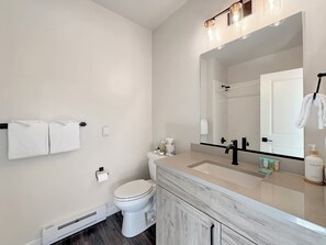 Een moderne badkamer met toilet, wastafel en spiegel.