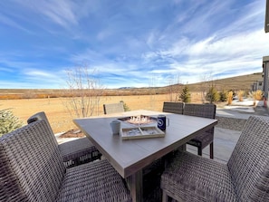 A patio with a table and chairs, a fire pit, and a view of a rural landscape. - Basecamp - Ski·Golf·Fish·Lake - Fire Table + Views (Granby)