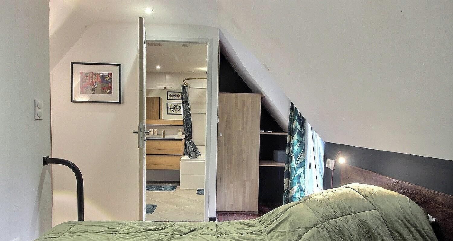 A bedroom with a bed, a door leading to a bathroom, and a staircase.