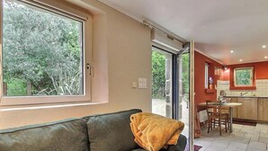 A living room with a sofa, a table, and a kitchen area visible through an open door. - Ty Forn - KERBORS - Gîte (KERBORS)