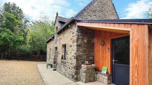 A stone building with a wooden extension, a door, and a small stone planter. - Ty Forn - KERBORS - Gîte (KERBORS)