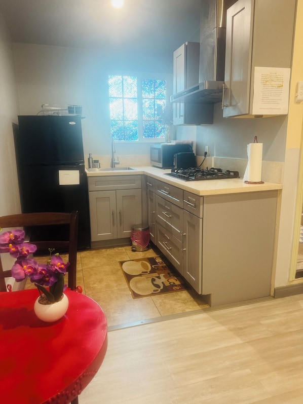 A compact kitchen with a refrigerator, microwave, stove, and cabinets.