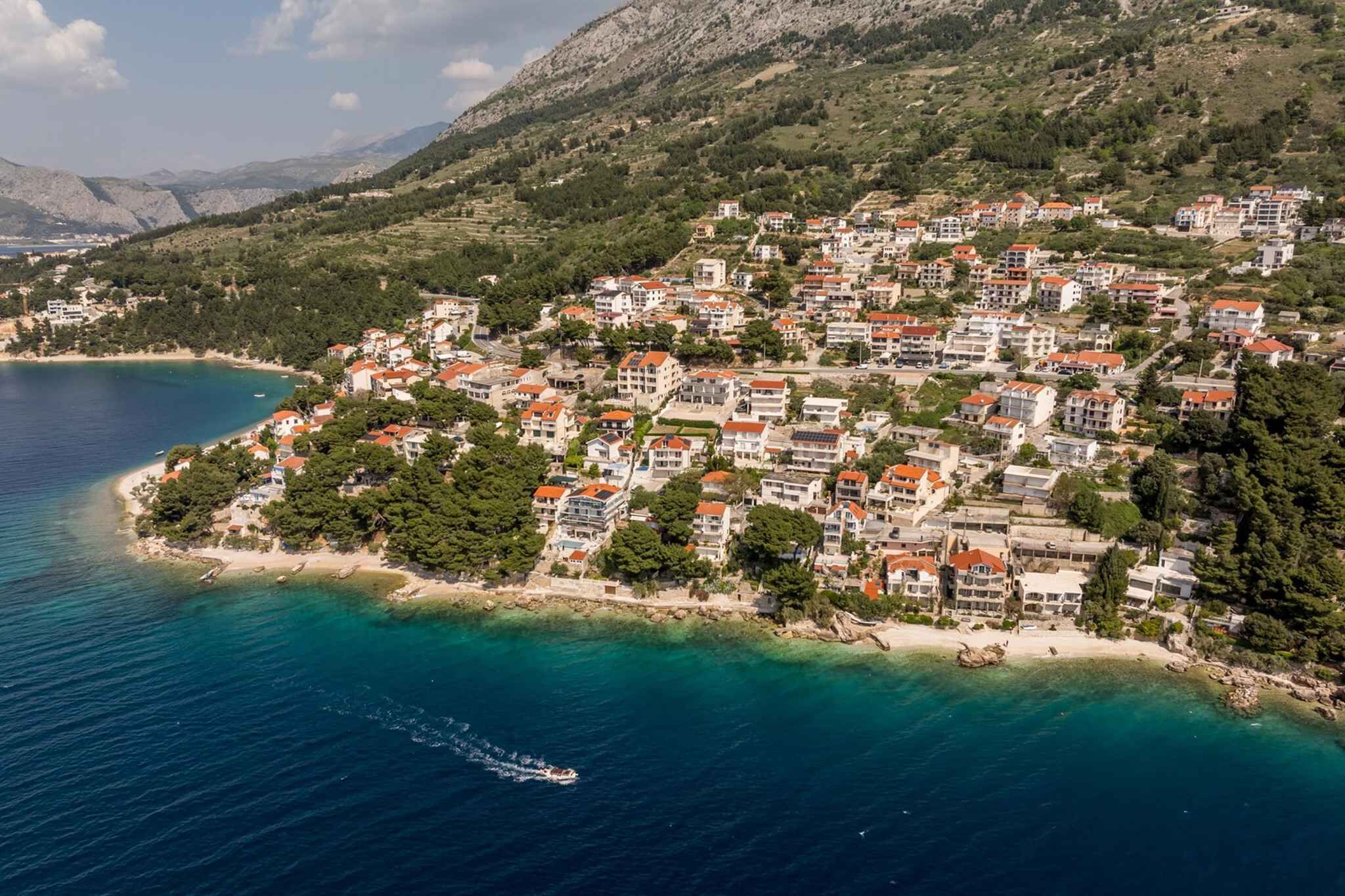 Une ville côtière avec des bâtiments, une plage et des montagnes en arrière-plan.