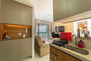 A modern kitchen with a built-in phone, a red appliance, and a sink. - 2-Bedroom Beachfront Apartment in the Center of Porto de Galinhas - Mirante de Porto 306 (Ipojuca)
