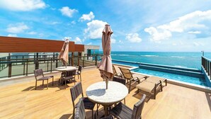 Eine Terrasse mit Sitzgelegenheiten im Freien, einem Pool und Blick auf den Ozean.