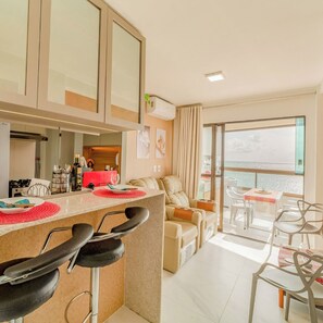 A modern apartment with a kitchen, dining area, and a balcony with a view. - 2-Bedroom Beachfront Apartment in the Center of Porto de Galinhas - Mirante de Porto 306 (Ipojuca)