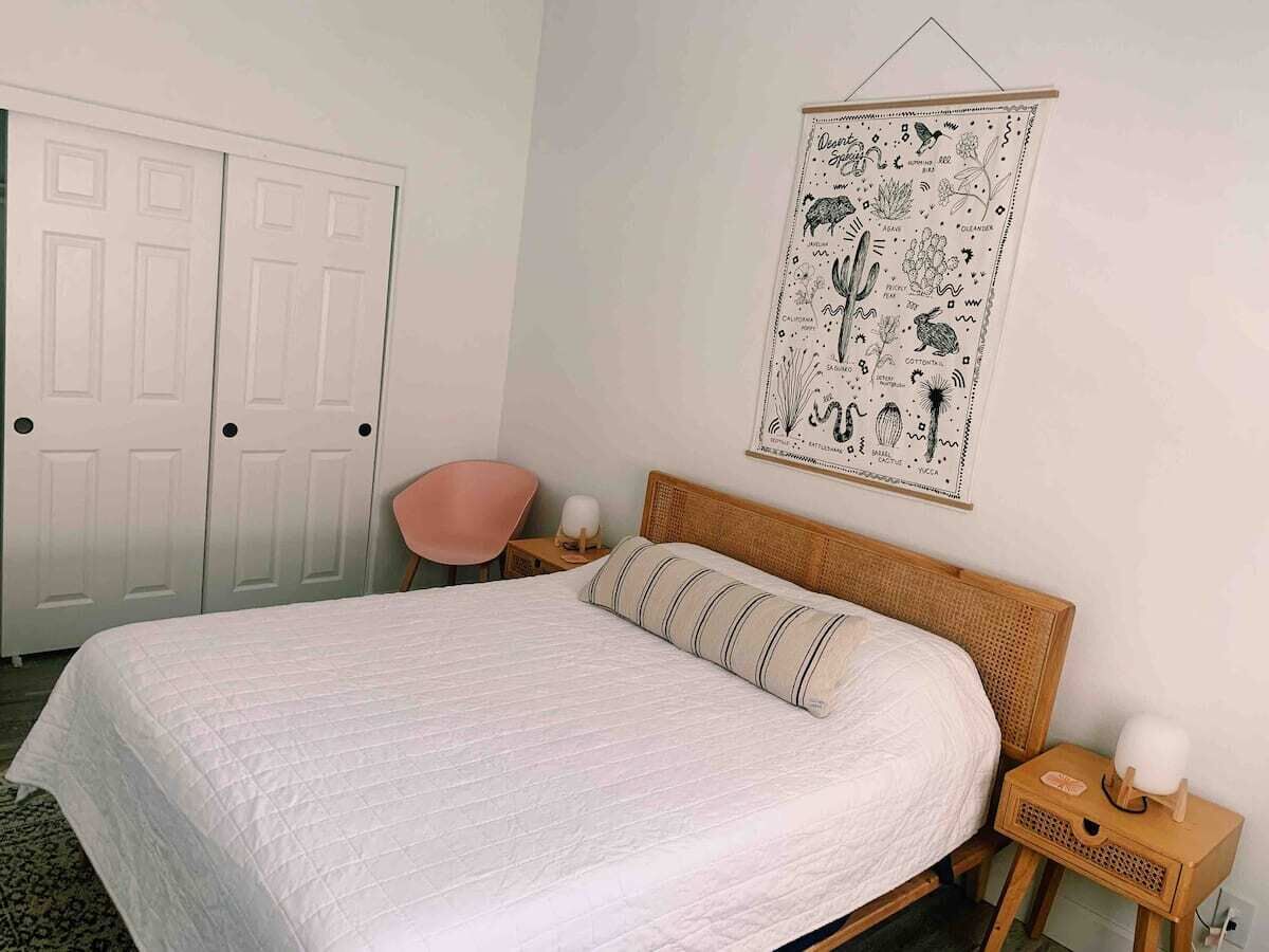 Une chambre à coucher comprenant un lit, une chaise, une table de chevet, une lampe et un objet décoratif mural.