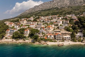 Un pueblo costero con edificios en una colina, una playa y aguas azules cristalinas.