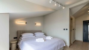 A modern bedroom with a large bed, bedside lamps, and a visible door. - Holiday Apartment Studio Ela 3 (Stanići)