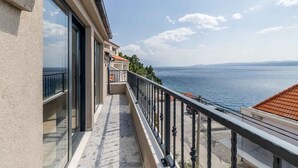 A balcony with a view of the sea, a building with large windows, and a clear sky. - Holiday Apartment Studio Ela 3 (Stanići)