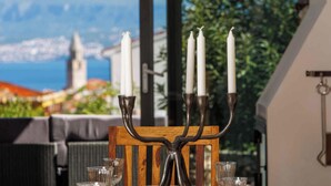 Ein Tisch mit einem Kerzenleuchter, Gläsern und Blick auf eine Küstenstadt.