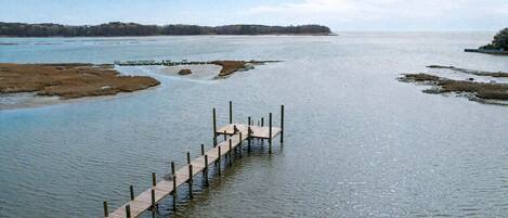 A wooden pier extending into a calm body of water with a distant shoreline.