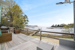 A wooden deck with outdoor seating, overlooking a body of water and distant land. - Blissful Oasis | Waterfront Seclusion with a Dock! (Exmore)