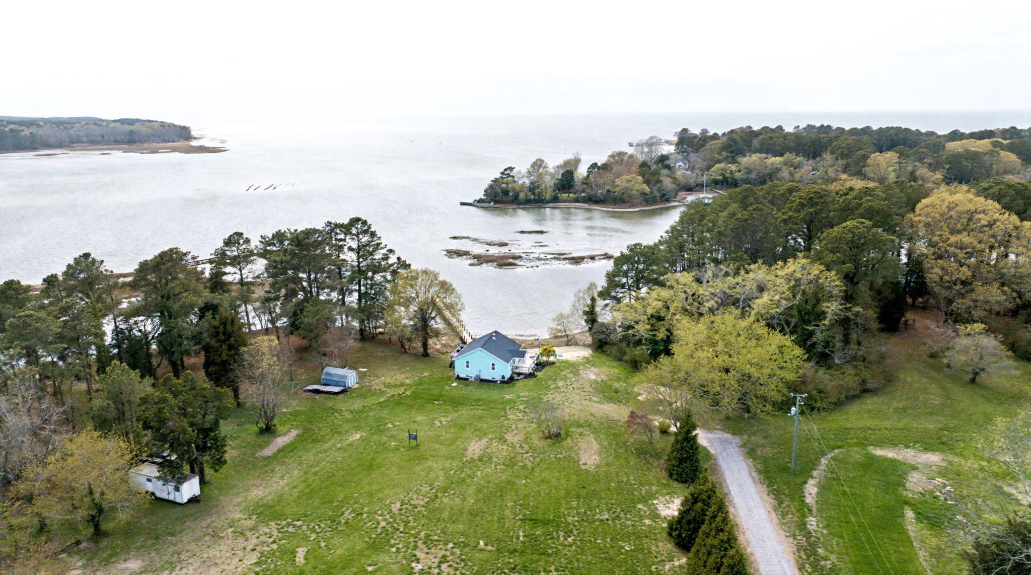 An aerial view of a property with a house, a boat, and a forested area near a body of water.