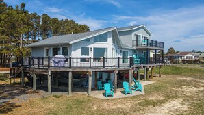A two-story house with a balcony, outdoor seating, and a view of the surrounding area. - Salty Oyster | Waterfront living at it (Chincoteague Island)