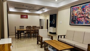 A modern living room with a dining area, a sofa, a coffee table, and a large abstract painting. - 2-bedroom villa in charming Thodupuzha with cool AC (THODUPUZHA)