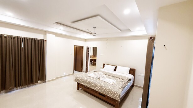 A spacious bedroom with a large bed, a ceiling fan, and a bathroom door. - 2-bedroom villa in charming Thodupuzha with cool AC (THODUPUZHA)