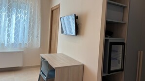 Ein Zimmer mit Schreibtisch, Stuhl, Fernseher und integrierten Regalen.