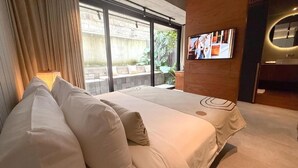 Una camera d'albergo moderna con un grande letto, una TV a parete e vista sull'esterno.