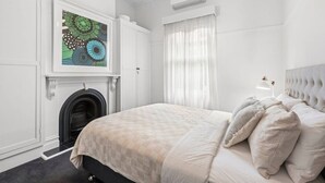 Un dormitorio con una cama, una chimenea, una ventana con cortinas y un equipo de aire acondicionado.