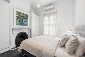 Quarto com cama, lareira, janela com cortinas e ar condicionado.
