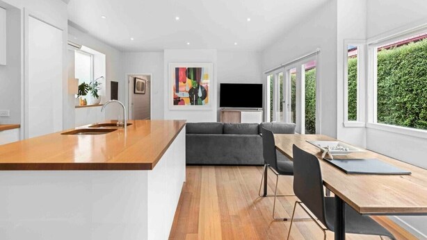 Una cocina moderna con encimera de madera y un sofá gris en la zona de comedor.