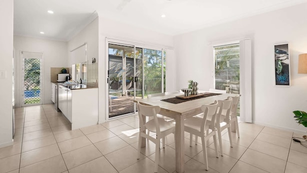 A modern kitchen with a dining area, large windows, and a ceiling fan. - Coastal 4-Bed Retreat with Pool in Toogoom (Toogoom)