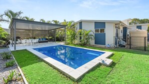 A modern house with a swimming pool, outdoor seating, and a covered patio. - Coastal 4-Bed Retreat with Pool in Toogoom (Toogoom)