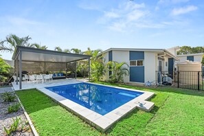 A modern house with a swimming pool, outdoor seating, and a covered patio. - Coastal 4-Bed Retreat with Pool in Toogoom (Toogoom)