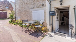 En bygning i sten med en hvid dør, en postkasse og et lille udendørs bord med stole.