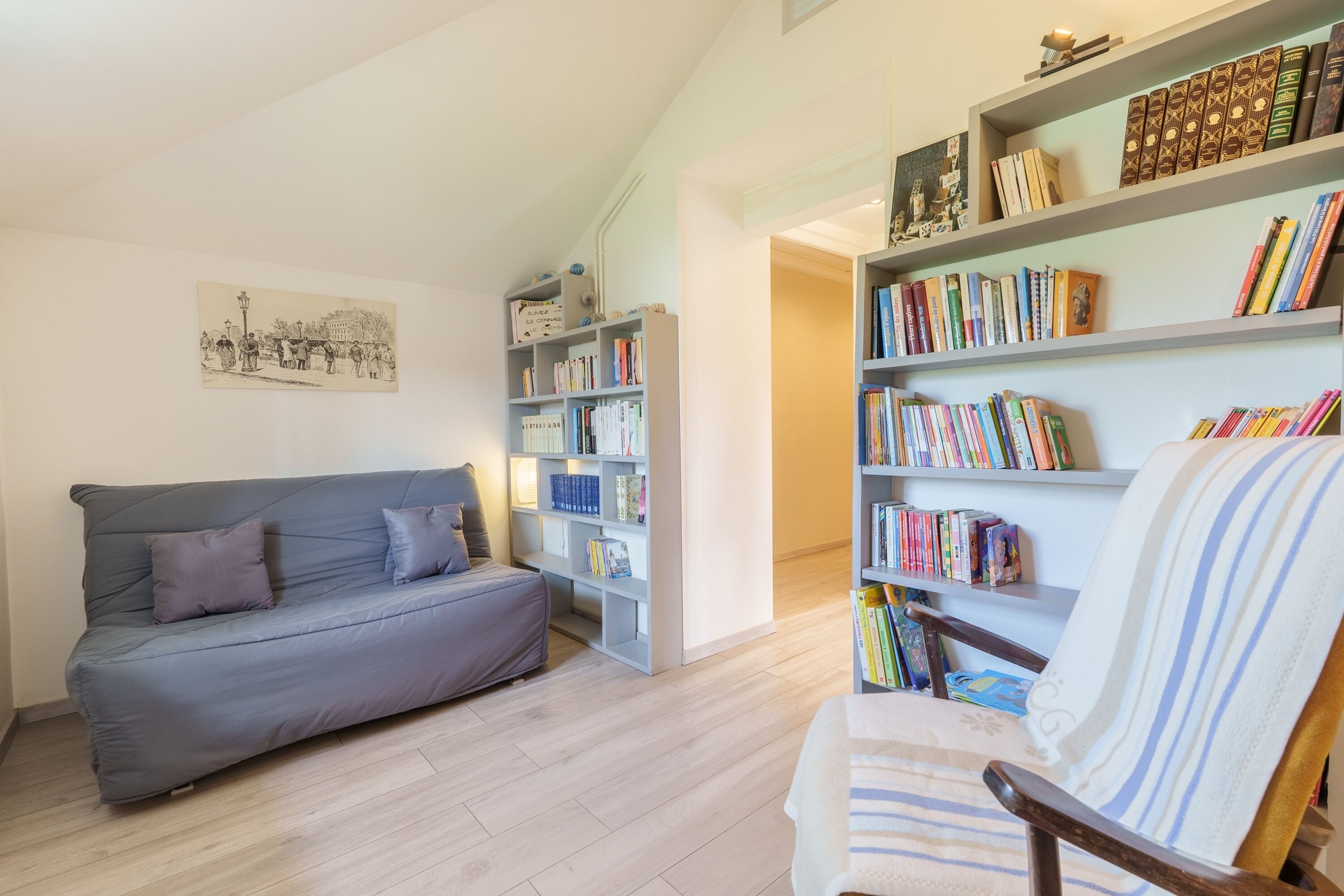 Una sala de estar con un sofá, una silla y estanterías llenas de libros.