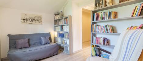 Una sala de estar con un sofá, una silla y estanterías llenas de libros.