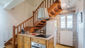 Una cocina con armarios de madera, horno empotrado, refrigerador, escalera de madera y ventana con vistas.