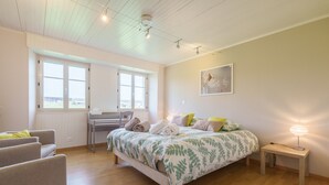 Un dormitorio con cama, mesita de noche, silla y escritorio con otra silla.