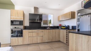 Una cucina moderna con mobili in legno, forno a incasso, microonde e frigorifero.