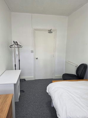 Ein Hotelzimmer mit Bett, Schreibtisch, Stuhl und Heizkörper.