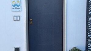 A dark-colored door with a small window above it, a welcome mat, and two potted plants on either side. - B&B Capo Vaticano Stay (Ricadi)