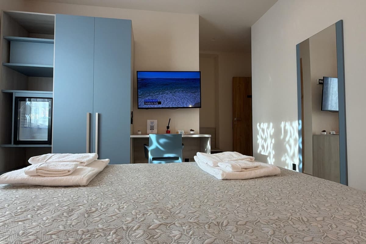 Una camera d'albergo con un letto, una scrivania, una televisione e un armadio.