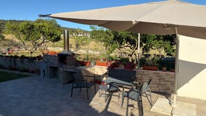 An outdoor patio with a brick oven, outdoor seating, and potted plants. - B&B Capo Vaticano Stay (Ricadi)