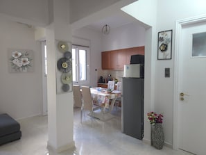 A modern kitchen with wooden cabinets, a refrigerator, and a dining area with a table and chairs.