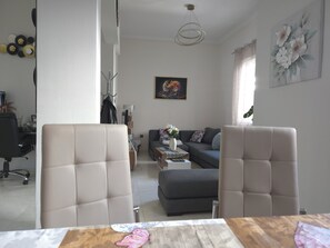 A living room with a sofa, two armchairs, a coffee table, and a painting on the wall.