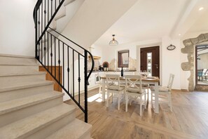 A staircase with a black railing leading to a dining area with a table and chairs. - Villa Franka with heated pool (Kvarner - Milohnići) (Milohnići)