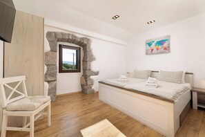 A bedroom with a stone archway, a bed with two pillows, a chair, and a world map on the wall. - Villa Franka with heated pool (Kvarner - Milohnići) (Milohnići)