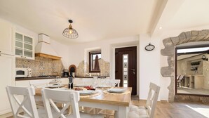 Una cuina moderna amb armaris blancs, taula de dinar de fusta i cadirees.