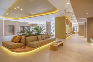 A modern interior with a curved sofa, a small wooden table, and a potted plant.