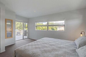 Ein Schlafzimmer mit einem großen Bett, einem Fenster mit Blick und einer Tür, die auf einen Balkon führt.