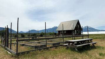 A rustic cabin with a metal roof, surrounded by a wooden fence and a picnic table.