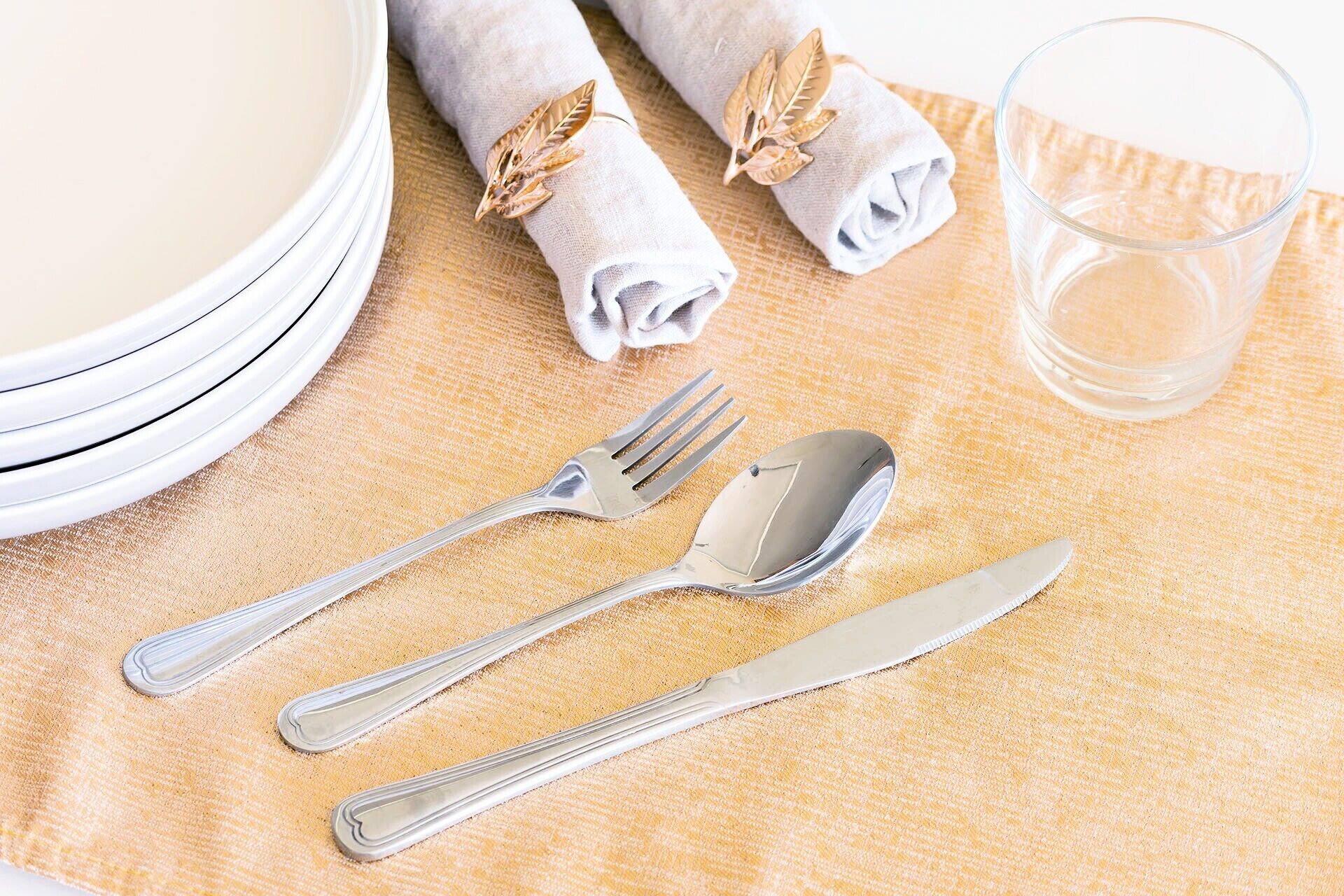A dining table with a folded napkin, a glass of water, and cutlery.