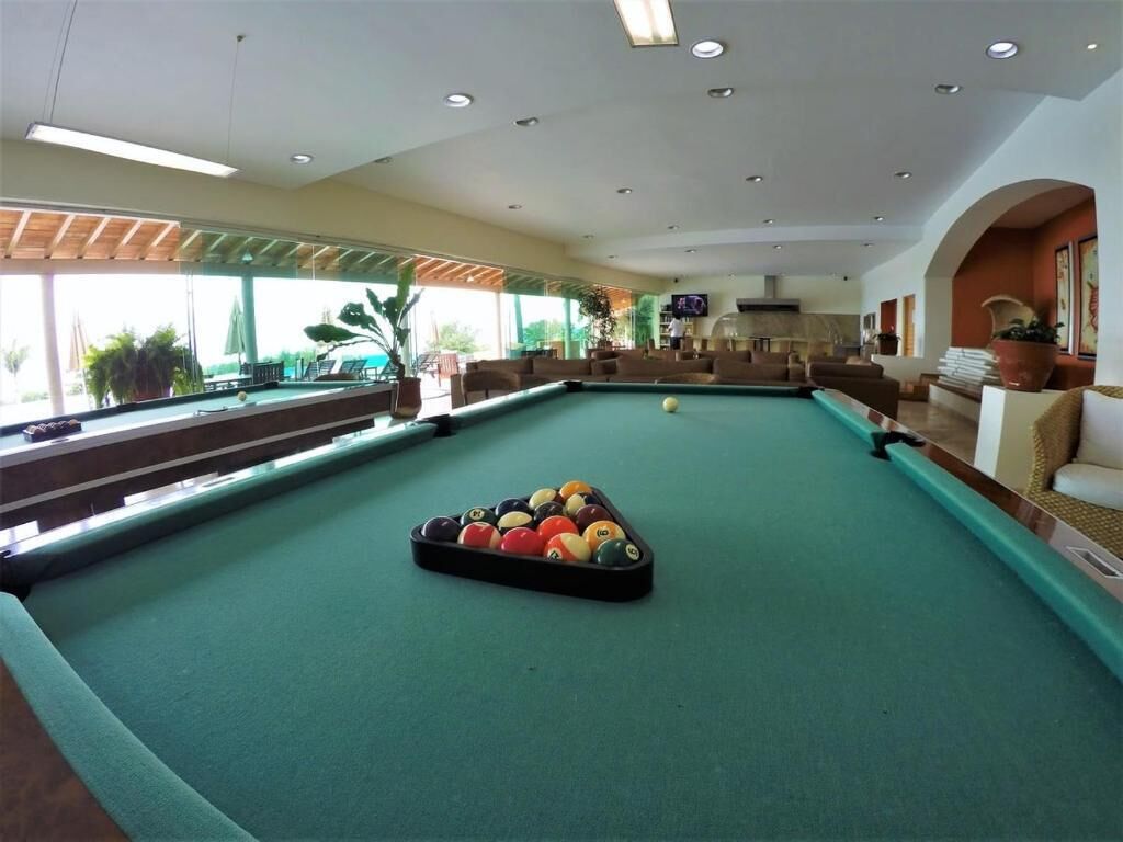 A pool table in a well-lit indoor area with a view of the outdoors.